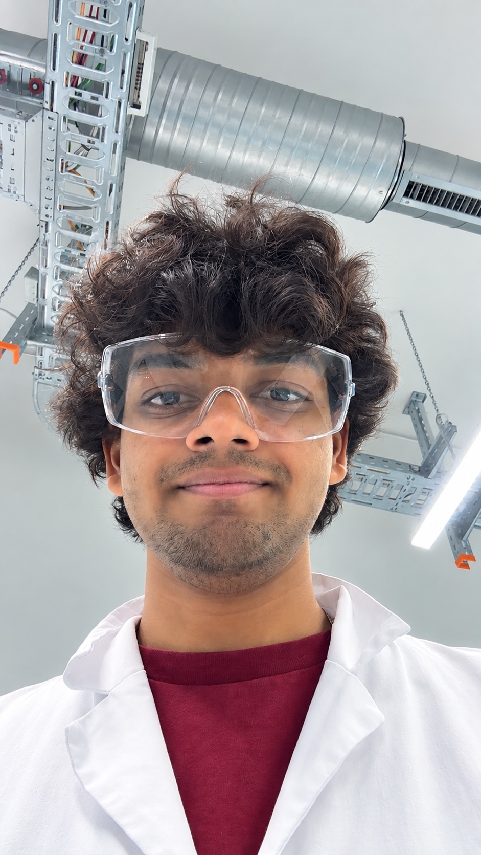 Ketan Chandra wearing a lab coat and protective glasses in a laboratory
